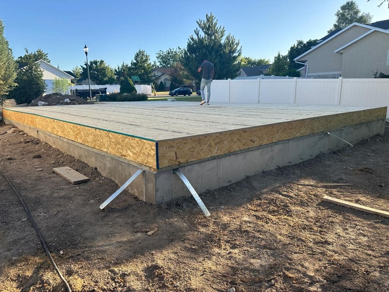 Concrete foundation with metal anchor straps and the subfloor edge