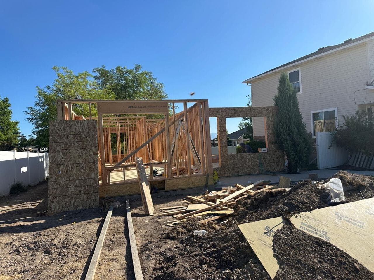 Framed walls with a window opening and lumber staged in front