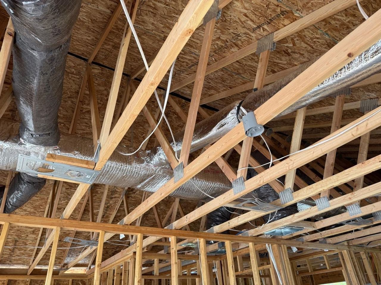 Insulated HVAC ductwork running through the roof trusses