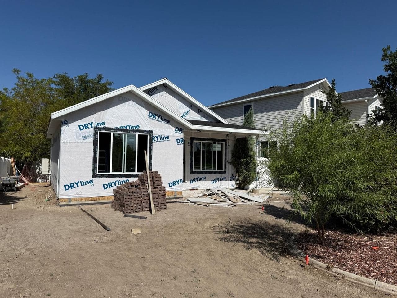 Front of the addition wrapped, with new windows and a siding pallet on site