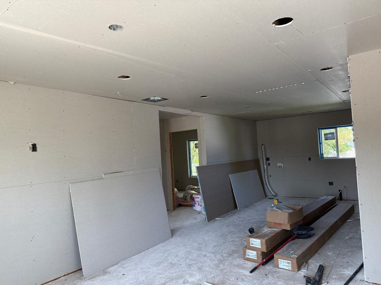 Interior with drywall hung on the walls and ceiling and sheets staged in the room
