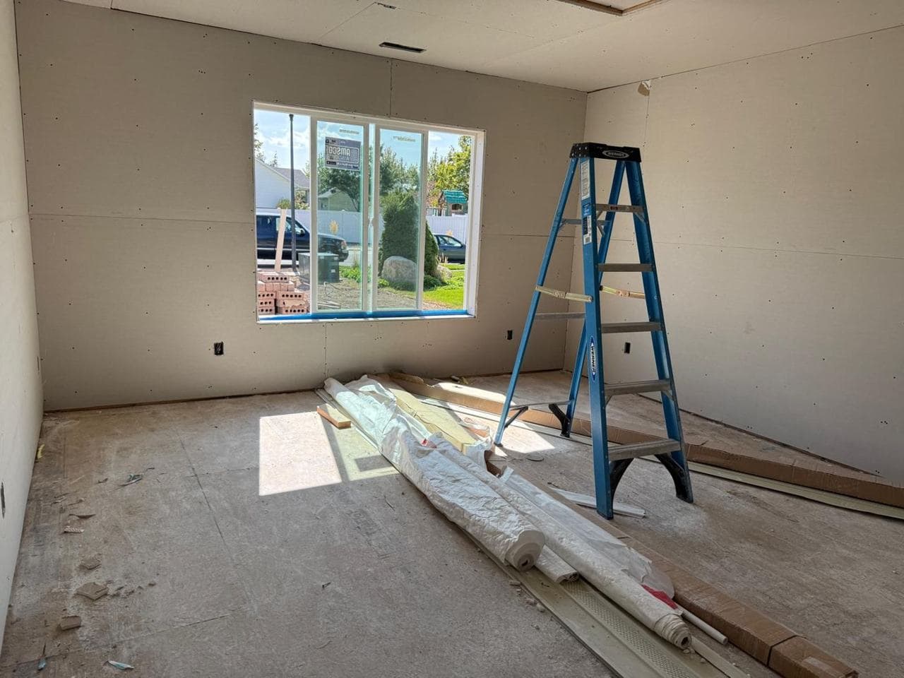 Bedroom-sized room with drywall, a large window and a ladder