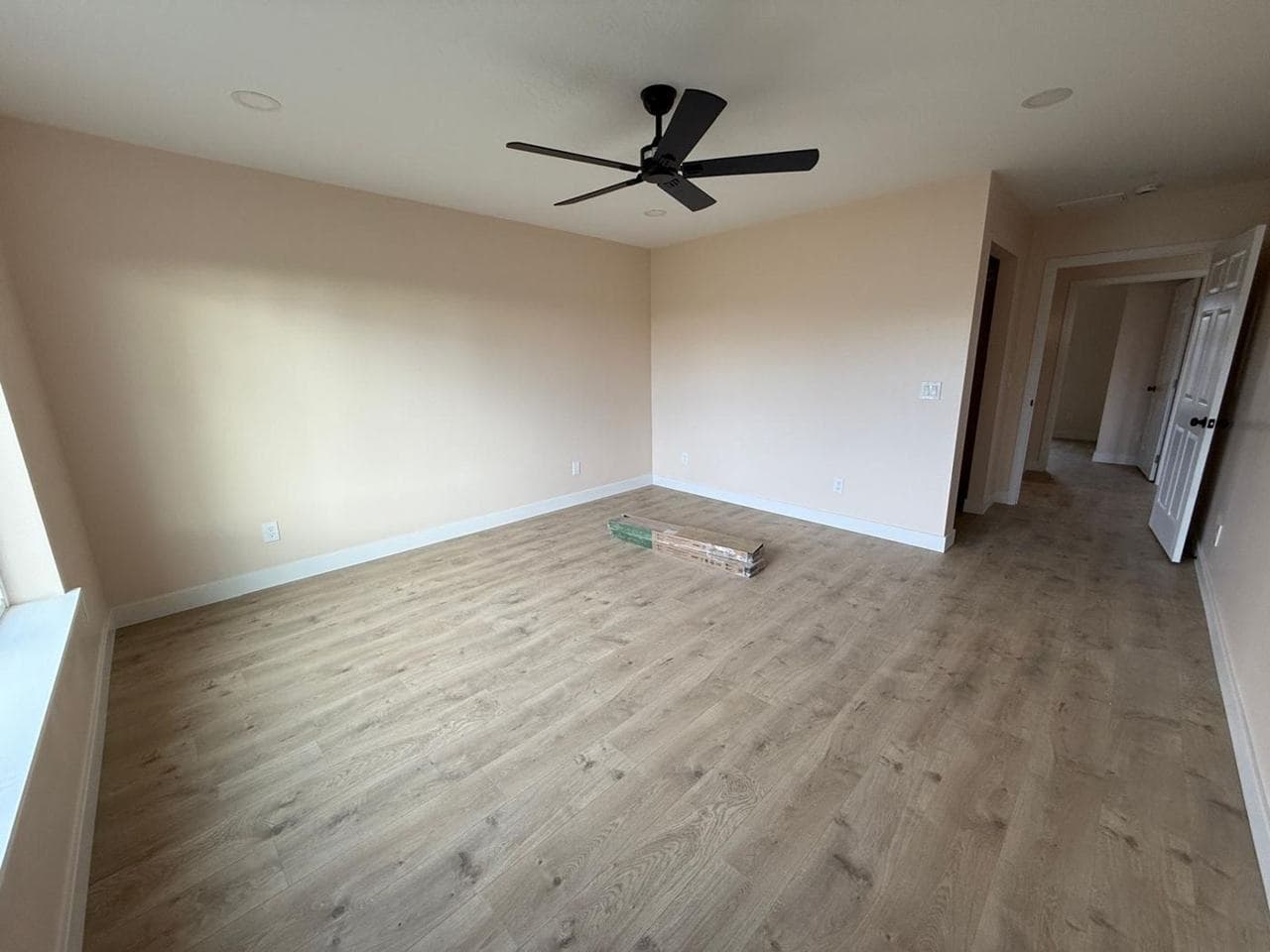Bedroom with wood-look flooring, ceiling fan and fresh paint