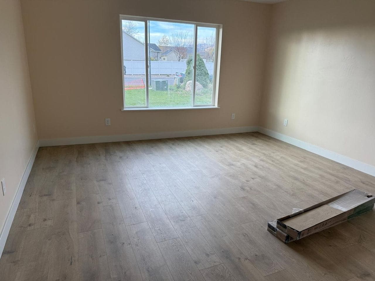 Finished room with a large window, baseboards and wood-look flooring